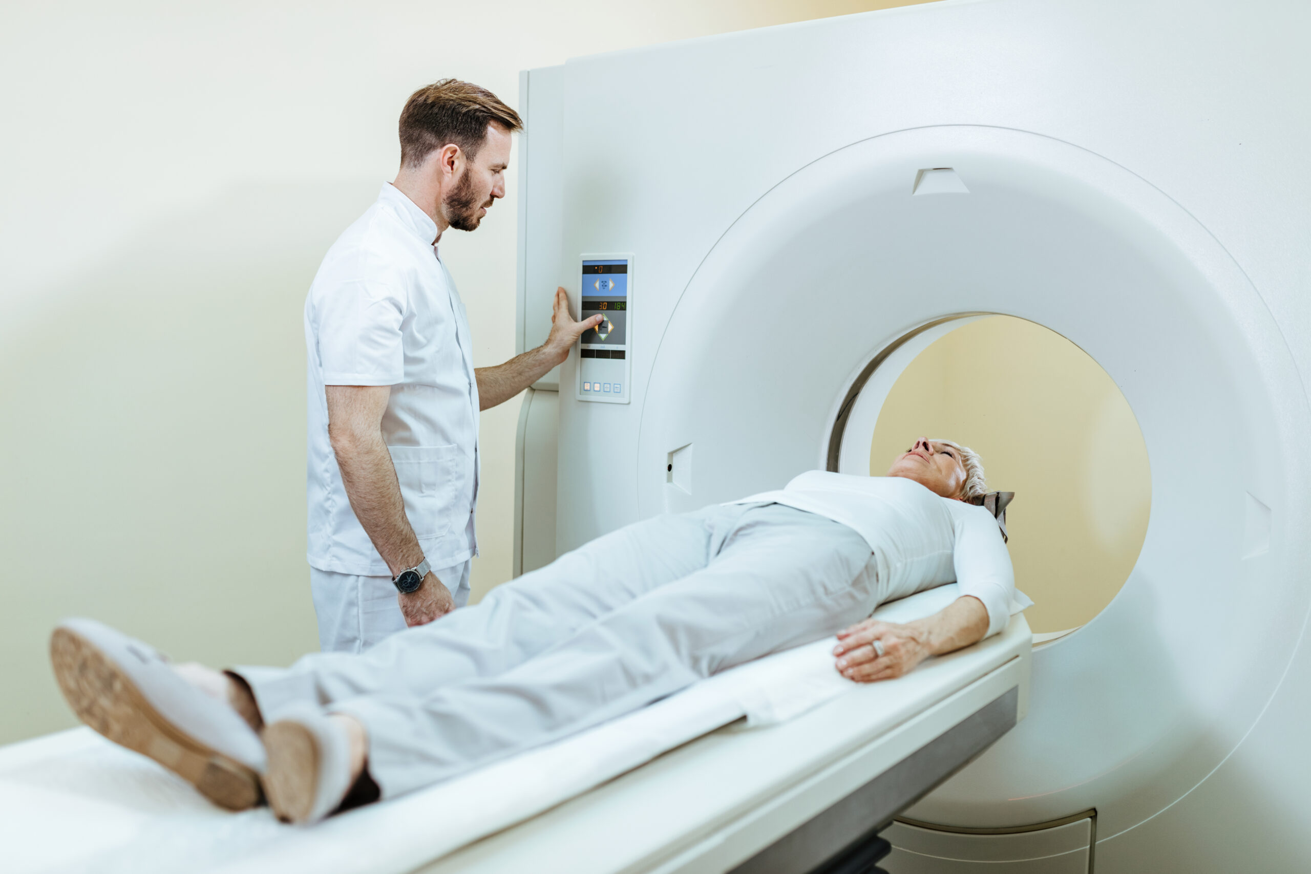 Radiologist preparing female patient for CT scan examination in